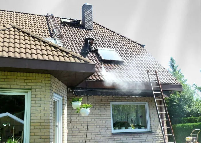 Mann steht auf Dach und reinigt es